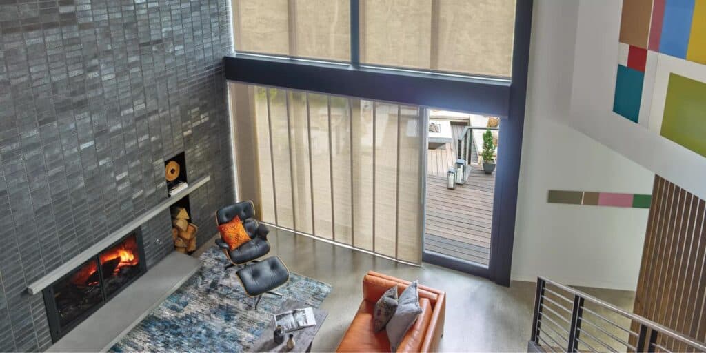 Bright, open-concept living space with floor-to-ceiling windows, gray accent wall, comfortable seating, and artistic interior design elements.