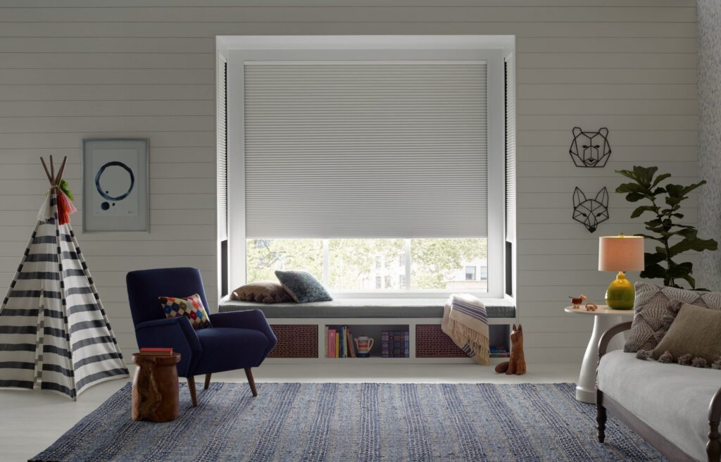Duette® Honeycomb Shades with the LightLock® system beside a chair in a kids’ room